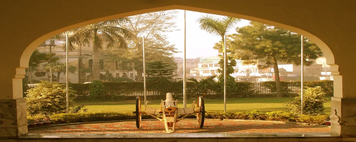 A field gun on the lawn, seen through a campus archway